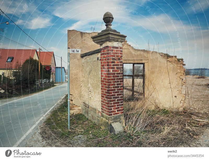 Erste Adresse Ruine Grundstück Haus Reste Fenster Mauer Mauerstück Pfeiler Backstein Straße Häuser Himmel Wolken Schönes Wetter Sträucher Erde Abrissgebäude