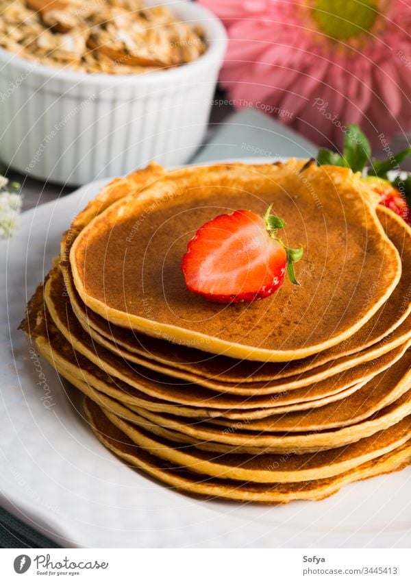 Stapel von Haferflocken-Pfannkuchen mit Erdbeeren Gesundheit Beeren Sommer Frühling Koch Blume Frühstück Morgen Mehl Sirup Ahorn Speise Teller weiß Tisch