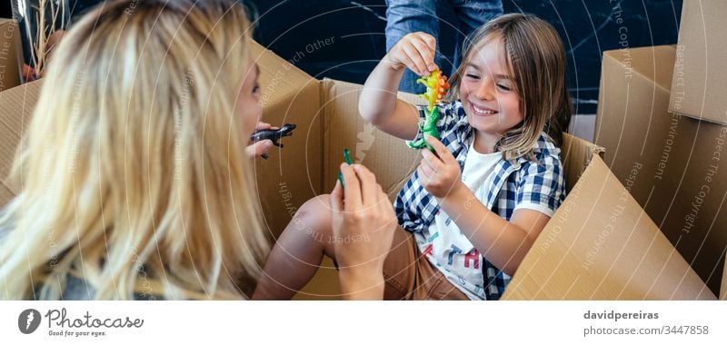 Mutter und Sohn spielen in einem Pappkarton Coronavirus Einsperrung panoramisch Spaß Spielen Dinosaurier Kasten Karton Quarantäne Kopfball zu Hause bleiben