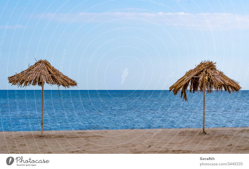 zwei Strohschirme an einer leeren Küste an einem klaren Tag Verlassen Herbst Bank Strand blau gebrochen Rohr übersichtlich Wolken Küstenlinie Beschädigte