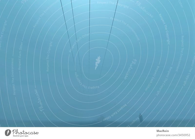 Mann im Nebel mann nebel nebelwand dunkel dunkelheit graublau alleine weg stille ruhig bedrückend landschaft ausserhalb draussen textfreiraum stromleitung