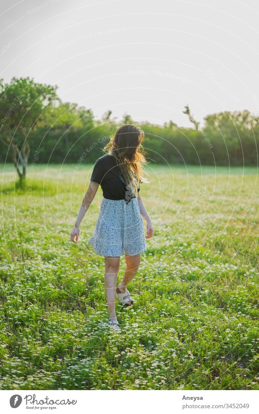 Eine junge Frau geht auf einem Feld mit kleinen Blumen 2017-2020 erste Einfuhr Junge Frau Mädchen elegant Freigeist Jugendliche Mensch feminin Stil schön