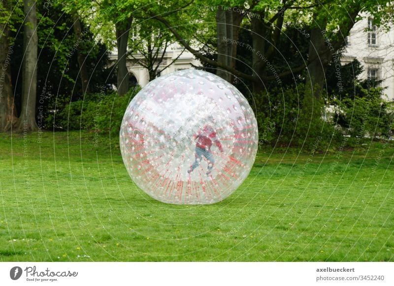 Unerkennbares Kind im Zorbing Ball zorb zorbing Park spielen Spielen Kindheit unkenntlich Spaß Sport Kugel Freude Aktivität Freizeit aufblasbar im Freien trendy