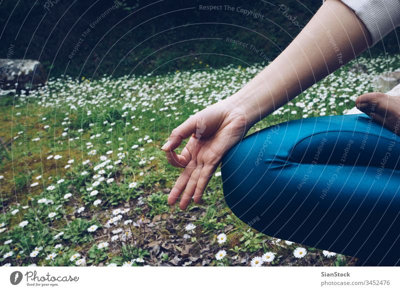 Junge Frau sitzt in Lotus-Pose, im Frühling mit Gänseblümchen im Freien Yoga Lotos jung Natur Meditation Margeriten Gesundheit Hintergrund Übung grün Gräser