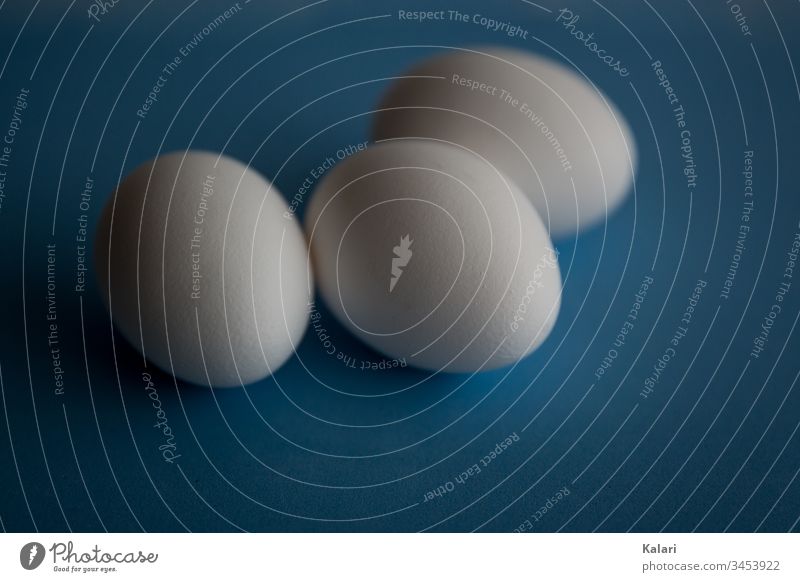 drei weiße Eier auf Blau ausblasen osterei blau minimalistisch unschärfe abstrakt schale eierschale ostern frühstück zerbrechen frisch bio eiweiß roh zutat