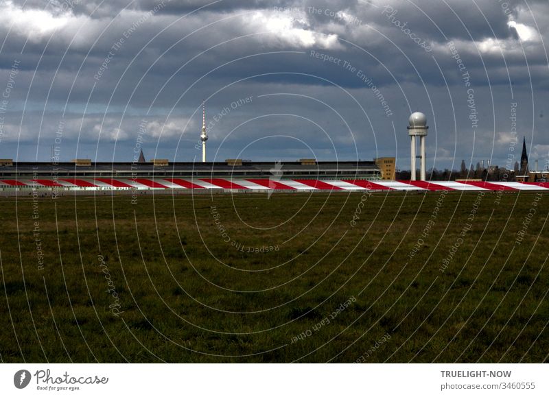 Berlin Tempelhofer Feld des stillgelegten Flughafens an einem düster bewölkten Tag mit Blick auf ein rot weißes Absperrband, auf das Hauptgebäude und den Berliner Fernsehturm im Hintergrund