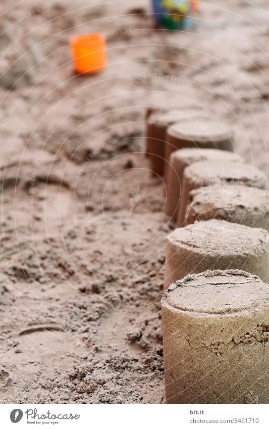 Sandkuchen oder Sandburg gebaut mit Sand am Strand oder im Sandkasten, im Urlaub, mit Eimer und Sandförmchen im Hintergrund. Küste Spielen Bauwerk