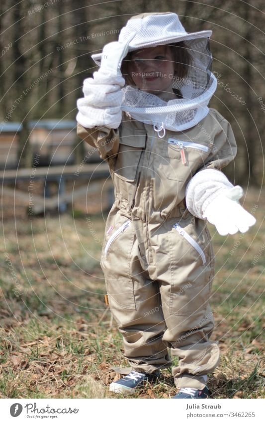 Kleines Kind im Imkerschutzanzug mit Handschuhen imkern Anzug Schutzanzug Hut Stolz süß Bienenstock Beute Wald Natur Waldlichtung Mädchen Kleinkind Turnschuhe