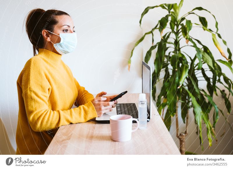 junge frau, die zu hause am laptop arbeitet und eine schutzmaske trägt. arbeiten sie von zu hause aus, bleiben sie während des coronavirus covid-2019 concpt sicher