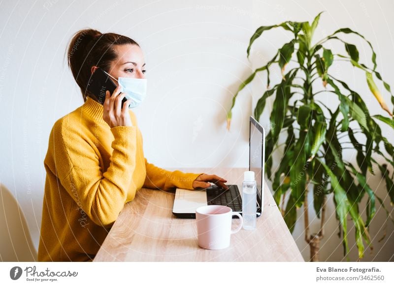 junge frau, die zu hause am laptop arbeitet und eine schutzmaske trägt. arbeiten sie von zu hause aus, bleiben sie während des coronavirus covid-2019 concpt sicher