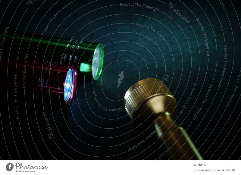 zwei farbige taschenlampen werden von der goldenen chef-taschenlampe kontrolliert Taschenlampe leuchten Dunkelheit Licht dunkel Kunstlicht schwarz Lichtquelle