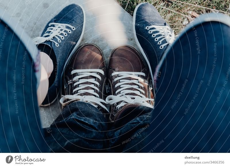 Junges Paar zeigt entspannt seine Füße in modernen Schuhen und bilden damit eine begeisternde Formation Vogelperspektive Starke Tiefenschärfe Sonnenlicht