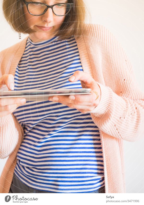 Lächelndes Mädchen mit Brille mit Tablette benutzend Smartphone Mobile Arbeit von zu Hause aus stayhome lernen Frau Schüler Beteiligung Business Behaarung