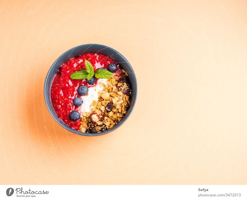 Joghurtschale mit Himbeeren auf Pfirsich-Orange Pastell Müsli Hafer Gesundheit lecker Konzept Smoothie Schalen & Schüsseln Blaubeeren gemischt Hintergrund