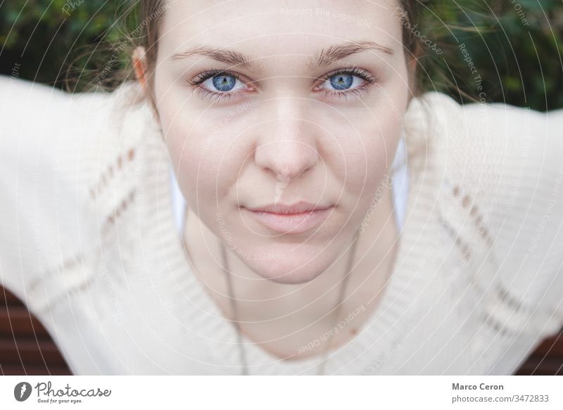 Nahaufnahme eines Mädchens, das ein weißes T-Shirt mit blauen Augen trägt und in ruhiger Pose aufmerksam in die Kamera schaut schön Schönheit blaue Augen