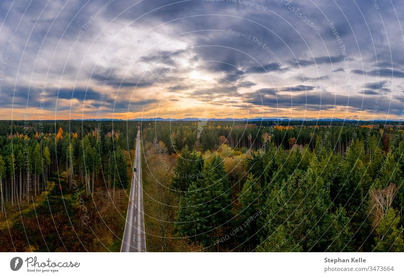 Luftaufnahme der Straße zwischen Wald und Bäumen. Sonnenuntergangsfeld in Süddeutschland in der Nähe der Alpen. Sonnenaufgang Baum Herbst Antenne