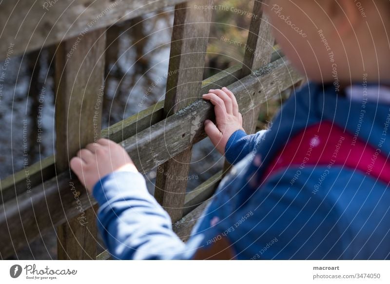 Kind hält sich an Geländer fest Corona draußen kind mädchen spielen draussen geländer kita absperrung zooz zaun natur wald spaziergang entdecken hand