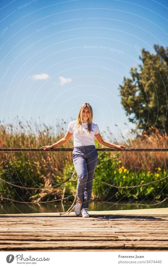 Junge elegante glückliche Frau posiert auf einem Pier Erwachsener Teenager blond kolumbianisch Spanien Mädchen jung attraktiv Tag stylisch im Freien Lächeln