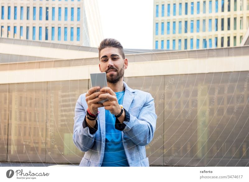 Porträt eines hübschen bärtigen jungen Mannes, der lächelt, wenn er sein Mobiltelefon benutzt Stil Typ Handy Sonnenbrille Hipster Lächeln 1 photogen Vollbart