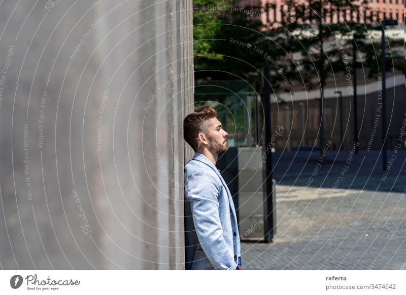 Nachdenklicher junger bärtiger Mann, der auf der Straße wegschaut, während er draußen an einer Wand lehnt Unsicherheit Geschäftsmann Denken Enttäuschung