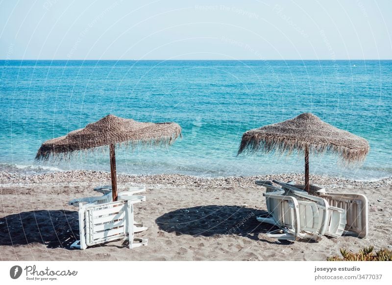 Regenschirme und leere Liegestühle, die im Sommer am Strand gesammelt werden. Hintergrund Strandkorb blau Stuhl Küste Küstenlinie Coronavirus covid-19