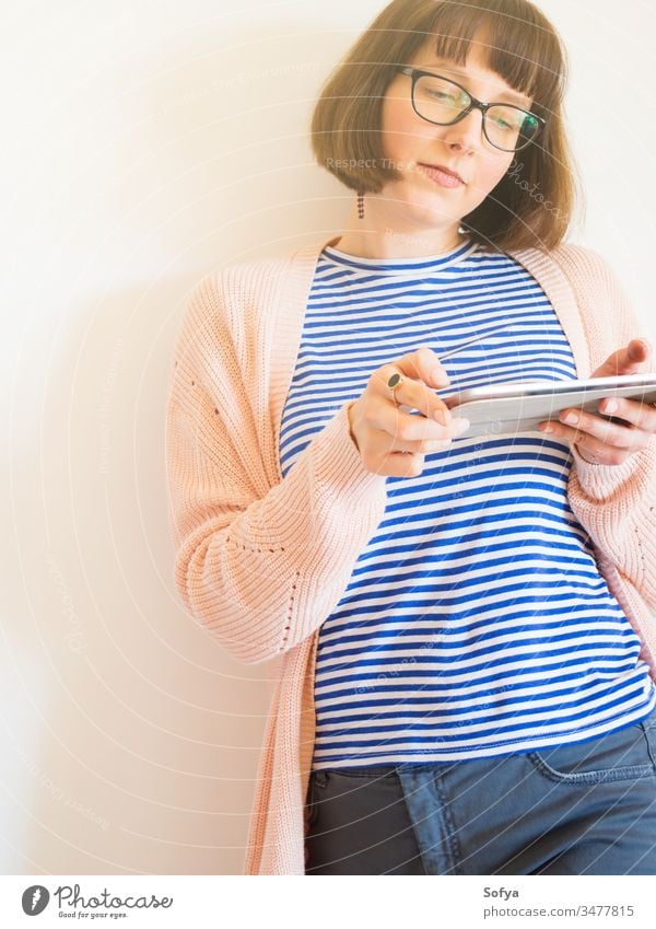 Lächelndes Mädchen mit Brille mit Tablette benutzend Smartphone Mobile Arbeit von zu Hause aus stayhome lernen Frau Schüler Beteiligung Business Behaarung