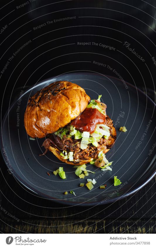 Hamburger mit Ketchup und Kräutern Feinschmecker Burger Brötchen Kraut Saucen Fleisch Teller dienen Lebensmittel Mahlzeit lecker geschmackvoll Mittagessen Küche