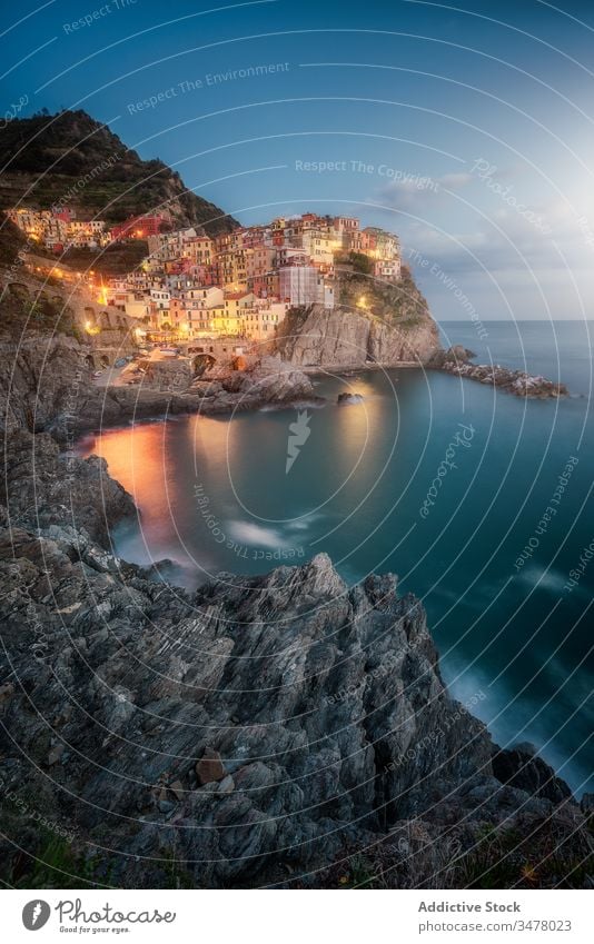 Erstaunliche Landschaft mit einer Kleinstadt mit bunten Lichtern an einer felsigen Küste, die nachts von ruhigem Ozeanwasser umspült wird Stadt MEER Nacht