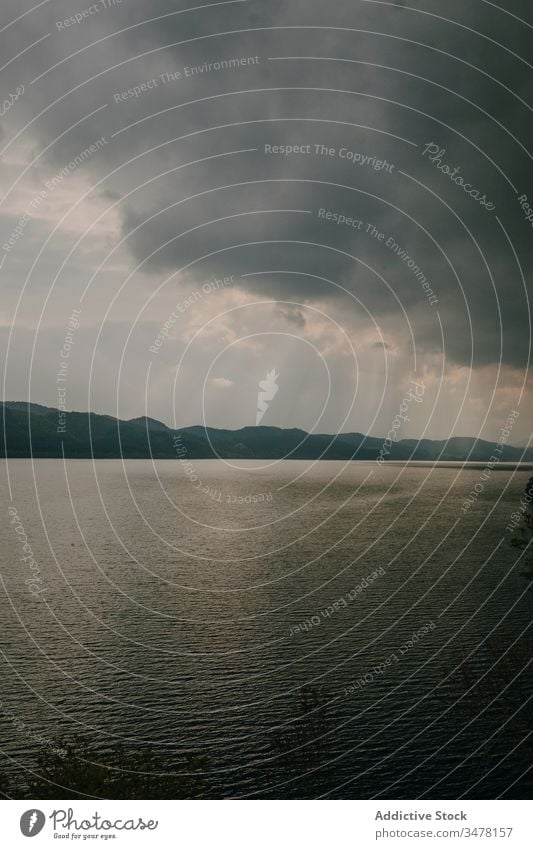 Ruhiger See unter bewölktem Himmel mit Sonnenstrahlen Cloud Rochen bedeckt Sonnenlicht dramatisch dunkel grau ruhig Landschaft Wasser Natur Oberfläche Rippeln