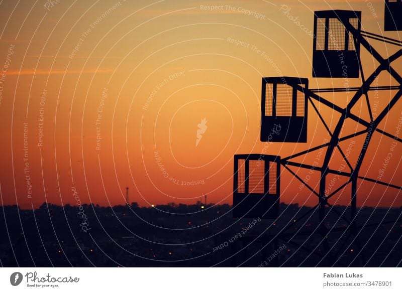 Altes Riesenrad im Sonnenuntergang über einer Stadt alt Schatten Silhouette orange gelb Himmel Außenaufnahme Menschenleer Abend