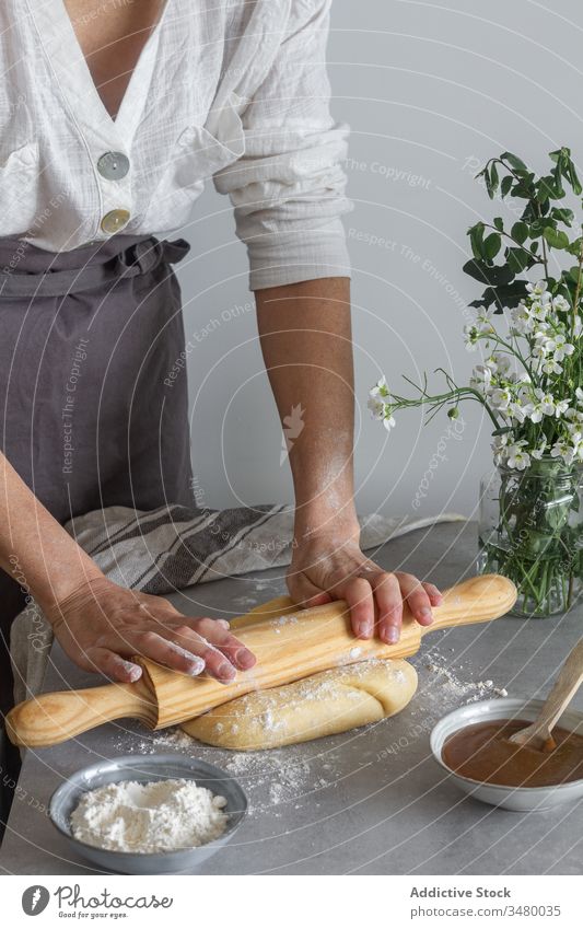 Weiblicher Teig für Blätterteig Frau Teigwaren rollen Gebäck Koch Nudelholz Tisch Mehl Apfel Püree Blume Blumenstrauß Schürze Werkzeug Utensil Küche vorbereiten