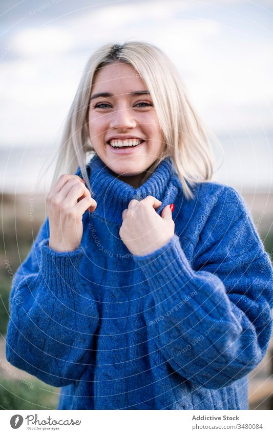 Fröhliche junge Frau im warmen Pullover blau Glück MEER Lachen positiv blond Freude Natur heiter Stil warme Kleidung gestrickt tausendjährig Feiertag charmant