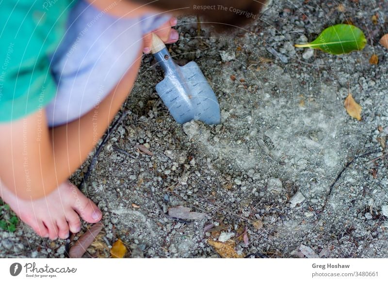 Barfüßiges Kind, das mit der Schaufel im Dreck wühlt Kinder Junge Sohn draußen spielen Schmutz Garten Gartenarbeit Außenaufnahme im Dreck spielen Menschen