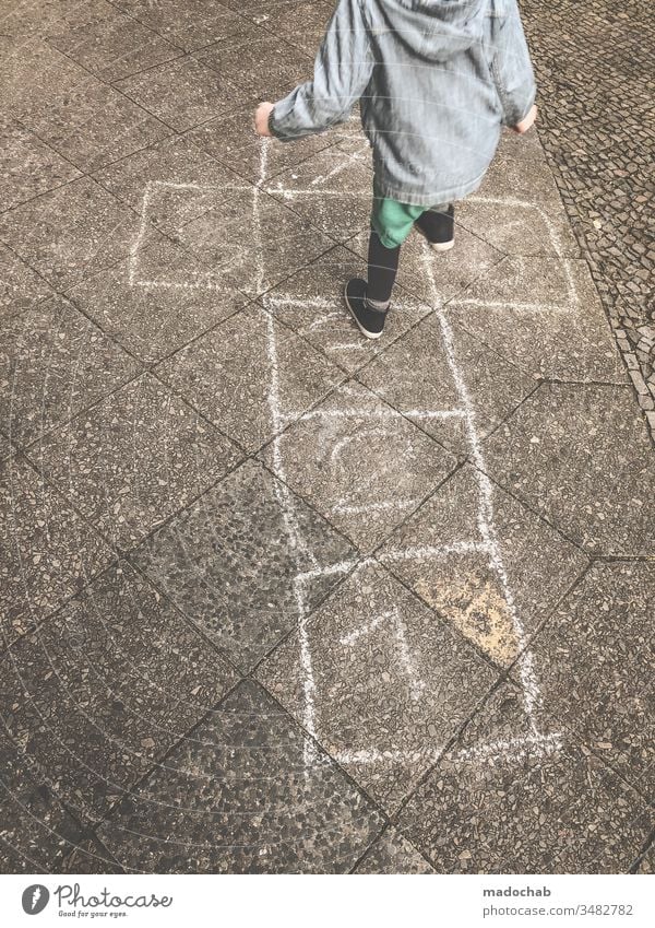 Hickelkasten spielen - Kind springt von Zahl zu Zahl auf mit Kreide gemalten Kästen - altes Kinderspiel Spiel hüpfen springen Spaß Außenaufnahme Spielen