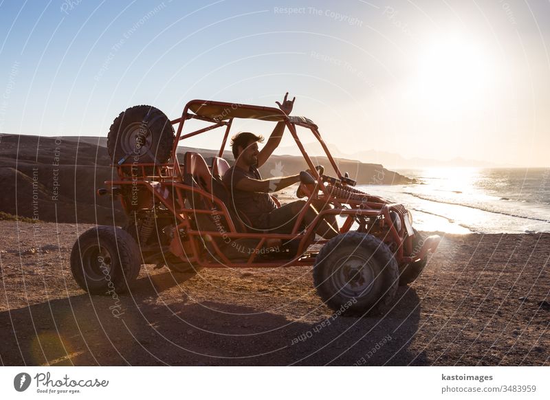 Mann fährt Quad bei Sonnenuntergang. quadbike vierfach Fahrrad Strand Abenteuer extrem Sand Sport Fahrzeug im Freien Spaß Mitfahrgelegenheit Meer zeigen