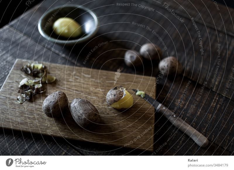 Pellkartoffeln auf Holzbrettchen mit Messer pellkartoffel schälen gesund geschält schale holzbrett kochen stilleben layflat messer alt pellen mittag anrichten