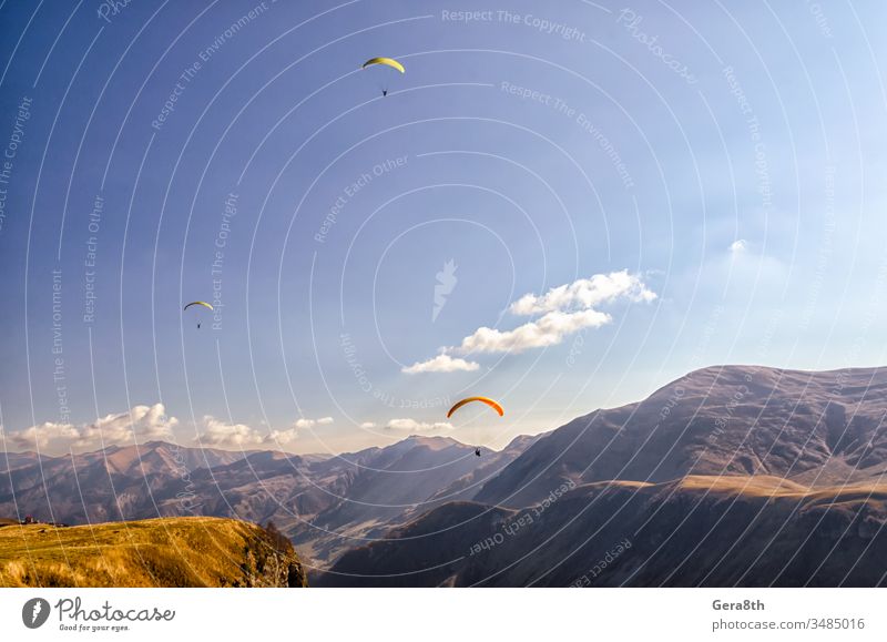 drei Gleitschirmflieger am Himmel vor dem Hintergrund der kaukasischen Berge Kaukasus Adrenalin Wolken Tag Europa extremal Extremsport Fliege fliegen Gras hoch