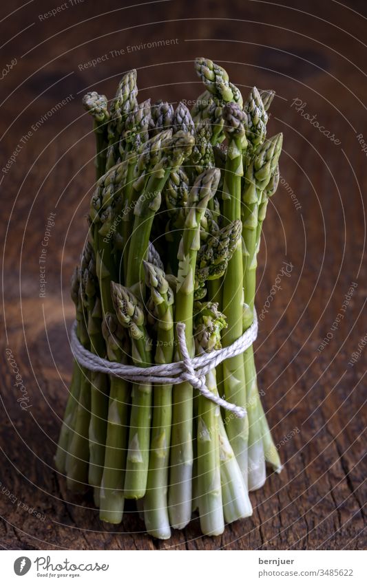 frischer grüner Spargel auf dunklem Holz Bündel Spargelbündel Planke Saison saisonal Gourmet String Küche Zutaten Antioxidans gesundes Essen Sprossen