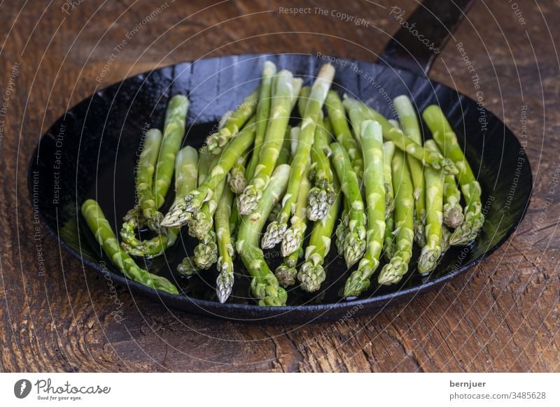 frischer grüner Spargel in einer Pfanne auf dunklem Holz Spargelpfanne Planke Saison saisonal Gourmet String Küche Zutaten Antioxidans gesundes Essen kochen