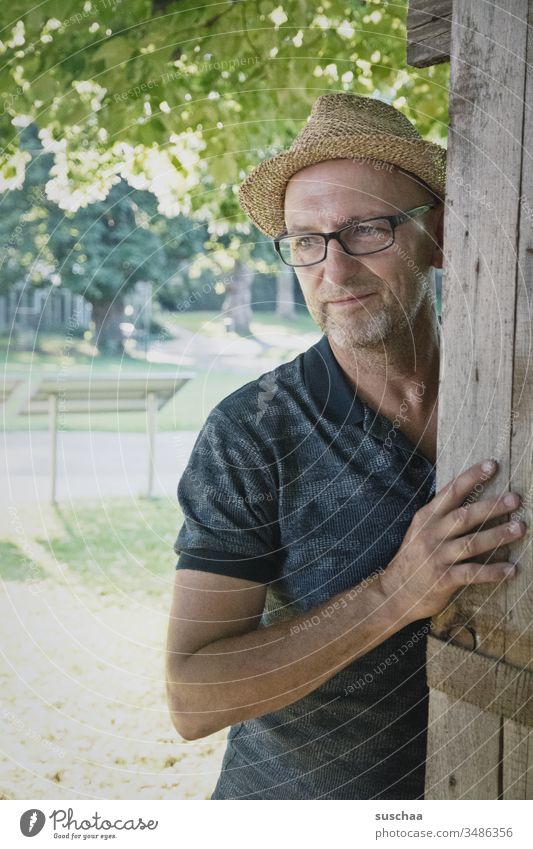 mann mit strohhut steht in einem sommerlichen park und schaut verträumt .. was mag er wohl denken? Mann Hut Strohhut Sommer Park Gelände Zoo Holzgestell