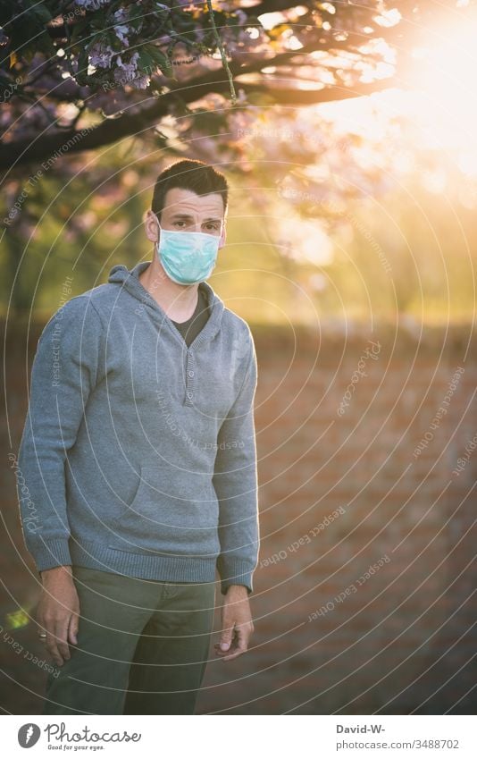 Maskenpflicht Corona Mann mit Mundschutz Atemschutzmaske draußen schaut in Kamera coronavirus Schutzmaske Virus verzweifelt Blick in die Kamera traurig Natur