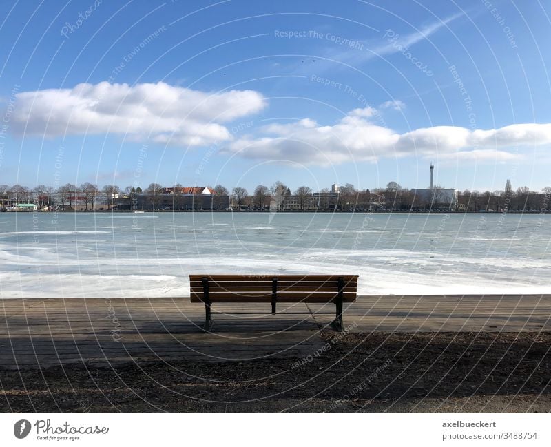 leere Bank mit Blick auf zugefrorenen Maschsee in Hannover Eis See Parkbank Winter Seeufer Aussicht Tag sonnig Kälte Einsamkeit Eisfläche kalt Frost Wasser