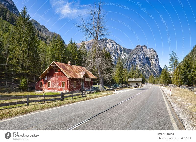 Rotes Gebäude an einer Straße in einer idyllischen Südtiroler Landschaft haus gebäude straße südtirol berge wald idylle landschaft dolomiten urlaub reise natur