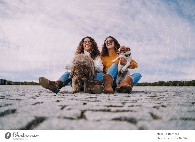 Zwei schöne Frauen sitzen mit ihren Haustieren im Park. Sie spielen und genießen einen gemeinsamen Tag. Es ist ein bewölkter Tag. zwei Hund freundlich Menschen