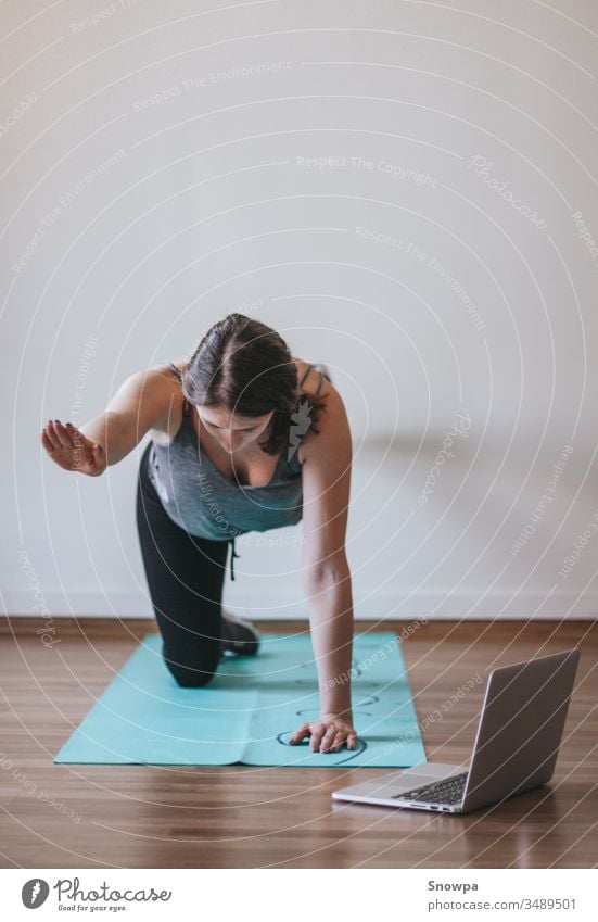 Junge Frau, die zu Hause Online-Yoga macht. Online-Fitness, Heimtraining. aktiv Erwachsener Asana Athlet sportlich attraktiv Hintergrund schön Körper Pflege