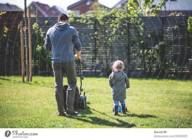 Familie - Vater und Tochter mähen im Garten den Rasen Kind Kindheit Mann Mädchen rasenmähen Rasenmäher Gartenarbeit Textfreiraum rechts niedlich harmonisch