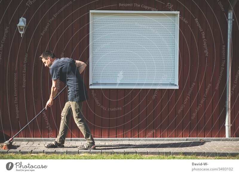 Mann fegt mit einem Besen den Weg fegen Wege & Pfade Garten Gartenarbeit Ordnung Sauberkeit sauber Ordnungsliebe aufräumen Besenstiel Wand