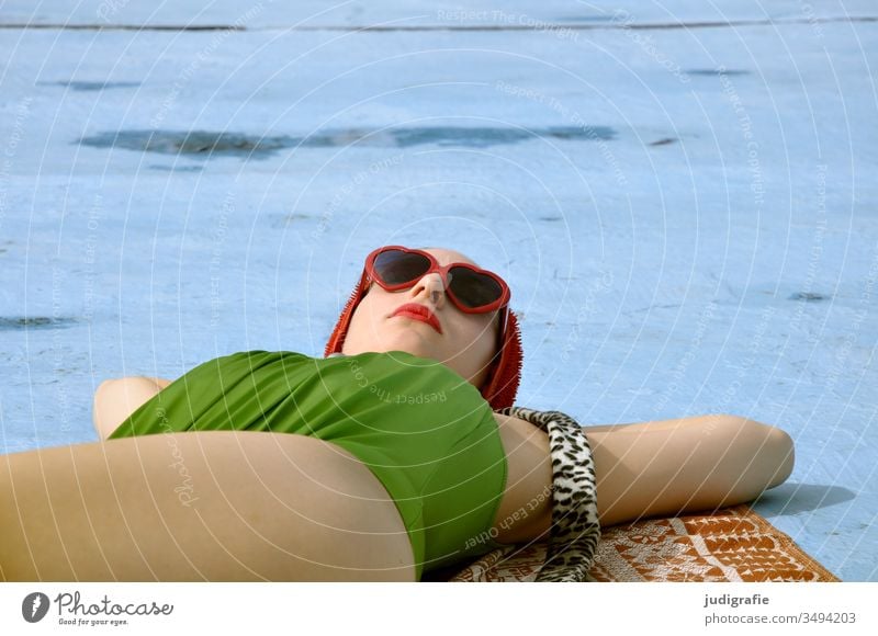 Das Mädchen mit der schönen roten Badekappe und grünem Badeanzug sonnt sich. Eine Sommerliebe. Frau Badebekleidung Badehaube Haut jung Schönes Wetter