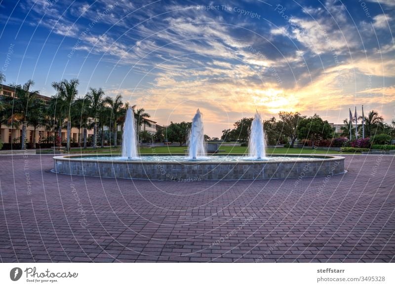 Sonnenuntergang über einem Springbrunnen mit drei Spritzern in einem reflektierenden Becken Landschaft Himmel Wolken Wasserfontäne reflektierender Teich Spray