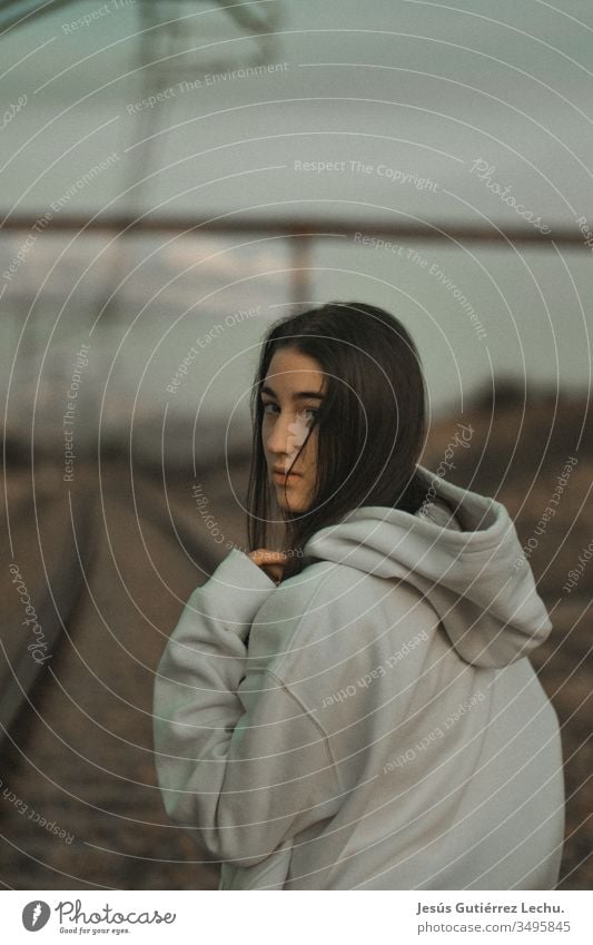 junge Frau mit Kapuze in einem weißen Sweatshirt mit ernstem Blick altehrwürdig Hintergrund Behaarung Gesicht Mädchen Menschen Außenaufnahme Beautyfotografie